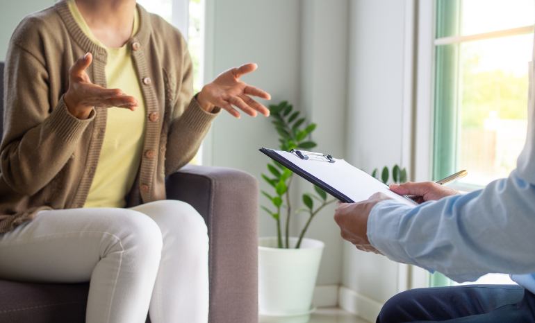 Woman in office with therapist writing on clipboard