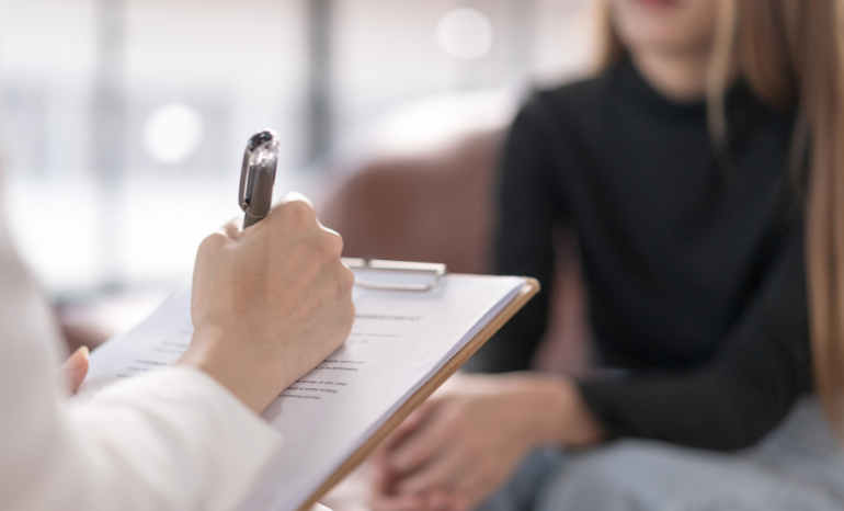 Person writing on clipboard in therapy