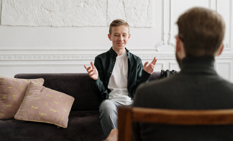 Young man in therapy with counselor talking with his hands