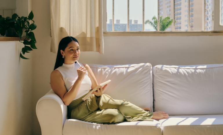 Woman on couch with notebook thinking